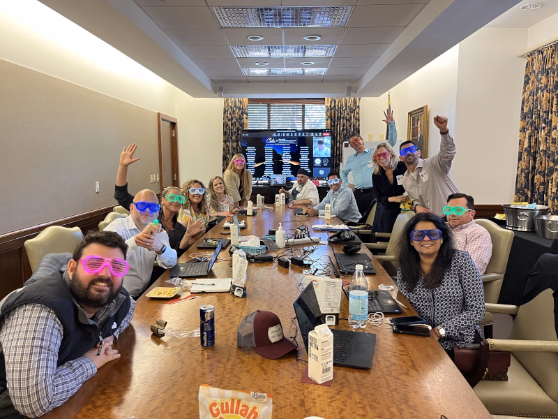 Smiling people celebrate in meeting room, sunglasses on.
