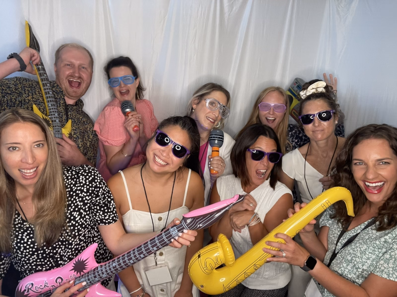 Laughing group poses with props in photo booth.
